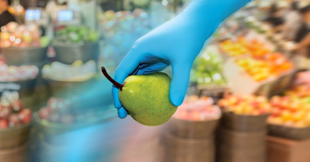 Microlite blue nitrile glove holding fruit in fresh food market